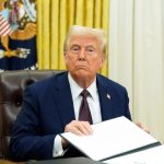 Donald Trump en su despacho presidencial sosteniendo lo que parece ser un acta