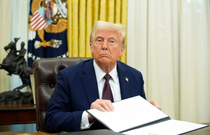 Donald Trump en su despacho presidencial sosteniendo lo que parece ser un acta