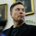 Elon Musk mirando hacia un lado mientras viste un pulcro traje color negro