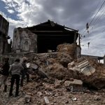 Una casa hecha pedazos y varias personas viendo y buscando heridos