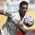 Jude Bellingham corriendo con el uniforme del Real Madrid y viendo fijamente un balon de futbol