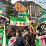 Muchas personas reunidas en procesiones mientras levantan banderas