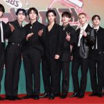 Los chicos de la agrupación musical con trajes negros de gala en una alfombra roja