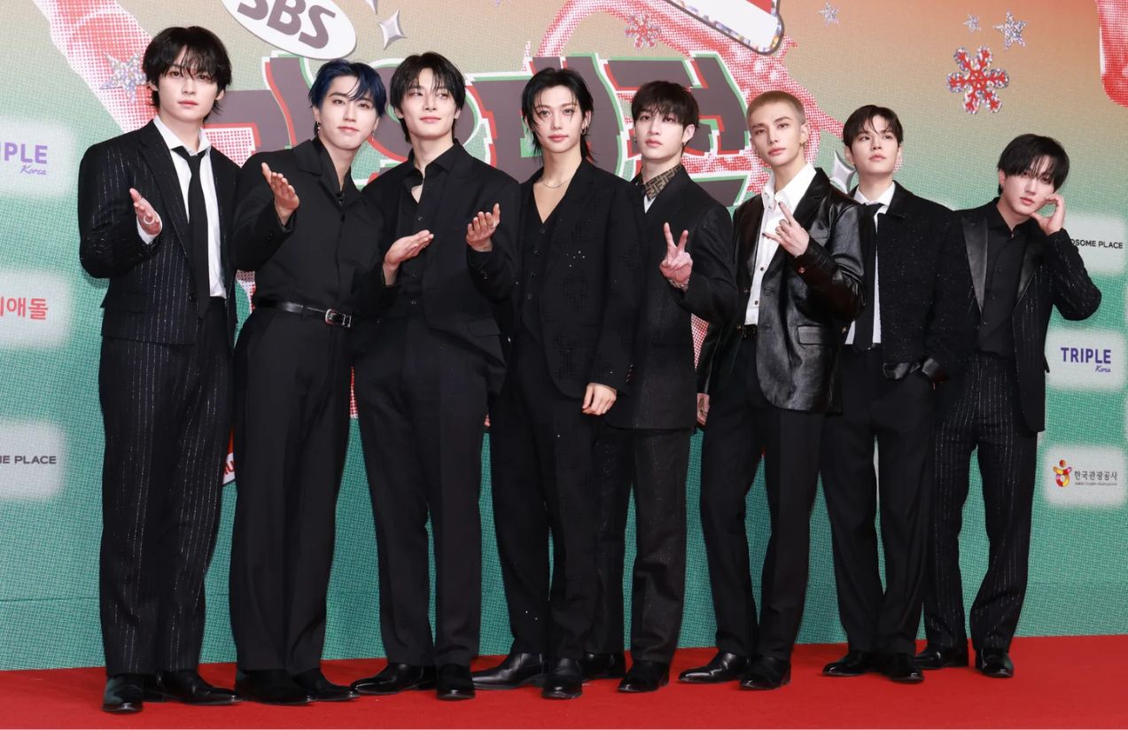 Los chicos de la agrupación musical con trajes negros de gala en una alfombra roja