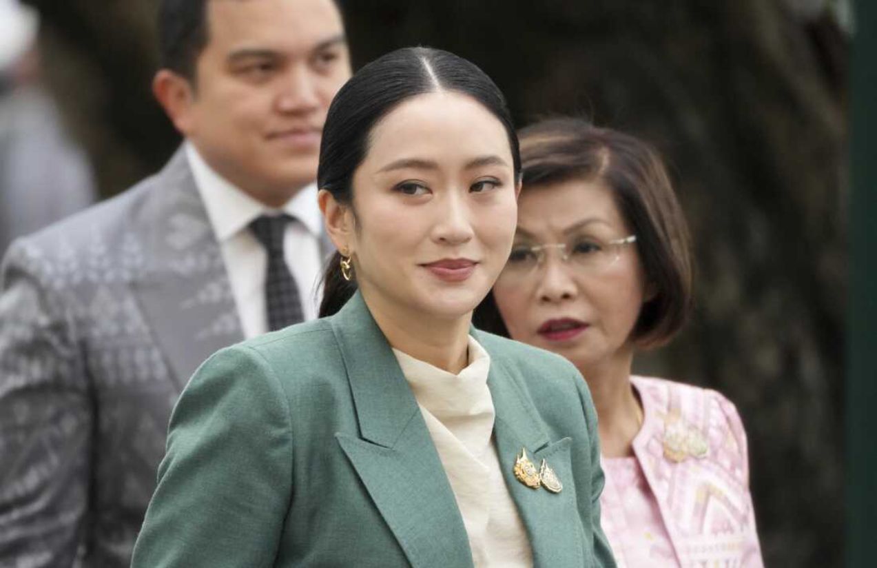 La primera ministra de Tailandia con un traje color verde y detrás varias personas