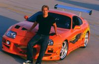 Paul Walker on the hood of his orange Toyota Supra