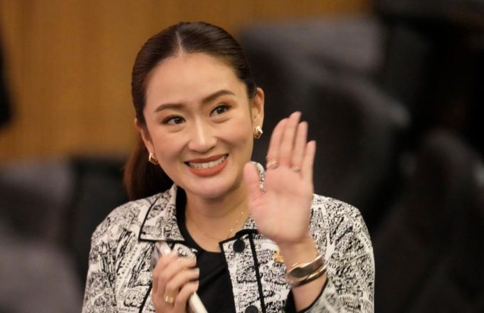 The Prime Minister of Thailand smiling and waving in court